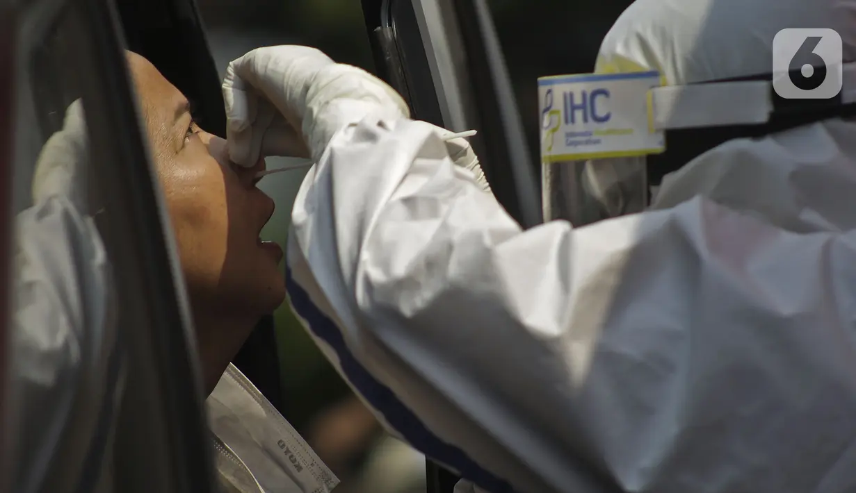 Petugas berpakaian APD lengkap melayani pasien yang secara mandiri melakukan swab test drive thru di halaman parkir rumah sakit di Jakarta, Rabu (12/5/2020). Swab test drive thru dilakukan untuk mendeteksi dan mencegah penyebaran virus corona COVID-19. (Liputan6.com/Johan Tallo)