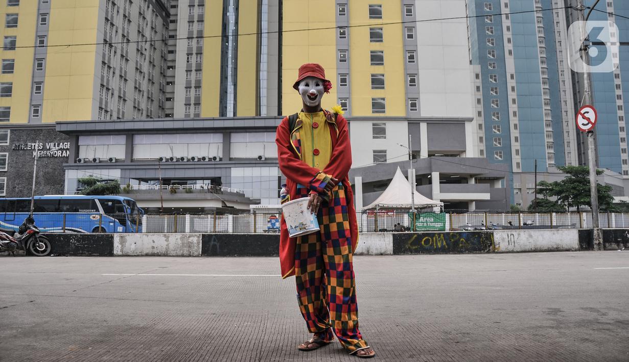 Badut melintas di dekat RSDC Wisma Atlet Kemayoran, Jakarta, Kamis (16/12/2021). Saat ini RSDC Wisma Atlet Kemayoran hanya digunakan untuk perawatan pasien Covid-19 dan satu tower dijadikan lokasi karantina atau isolasi terpusat bagi pekerja migran indonesia atau TKI. (merdeka.com/Iqbal S. Nugroho)