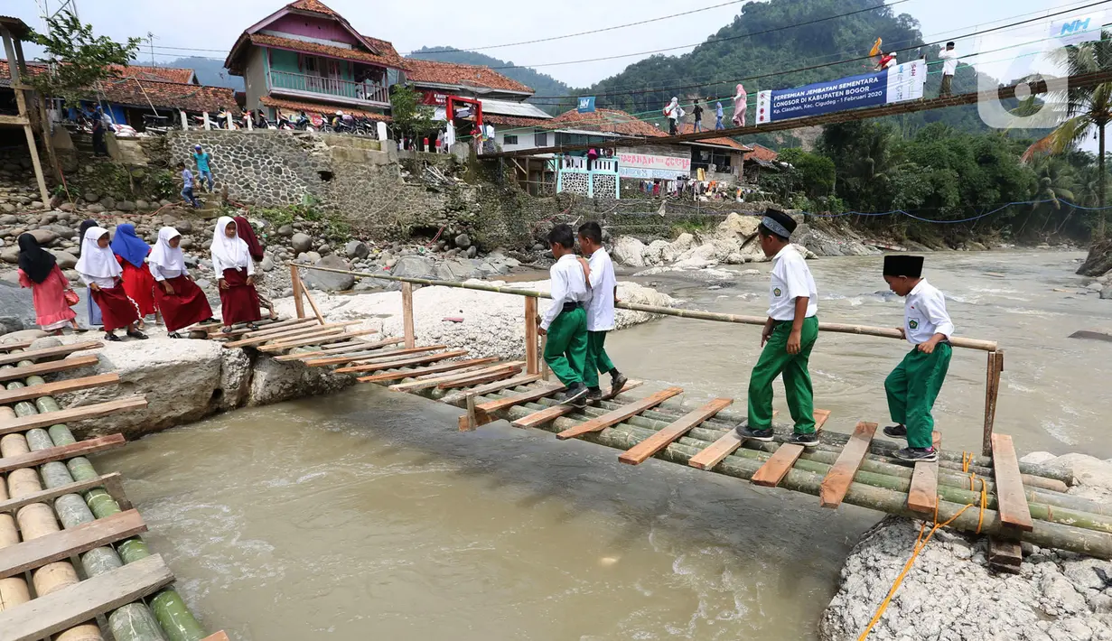 Siswa melintasi jembatan darurat berbahan bambu di Kampung Ciasahan, Desa Sukamaju, Kabupaten Bogor, Kamis (6/2/2020). Pembangunan kembali jembatan Ciasahan yang ambruk akibat banjir bandang pada Rabu (1/1) itu diharapkan mampu memulihkan aktivitas dan perekonomian warga. (merdeka.com/Arie Basuki)