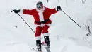Pemain ski berpakaian Santa Claus menuruni lereng gunung saat Santa Sunday ke-19 di Newry, Maine, AS, Minggu (2/12). Tahun ini, keuntungan Santa Sunday mencapai 4 ribu US dolar atau senilai hampir Rp 57 juta. (AP Photo/Robert F. Bukaty)
