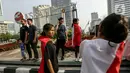 Warga yang mengenakan bendera Merah Putih untuk membalut tubuhnya berswafoto saat  CFD di Jakarta. (Liputan6.com/Faizal Fanani)