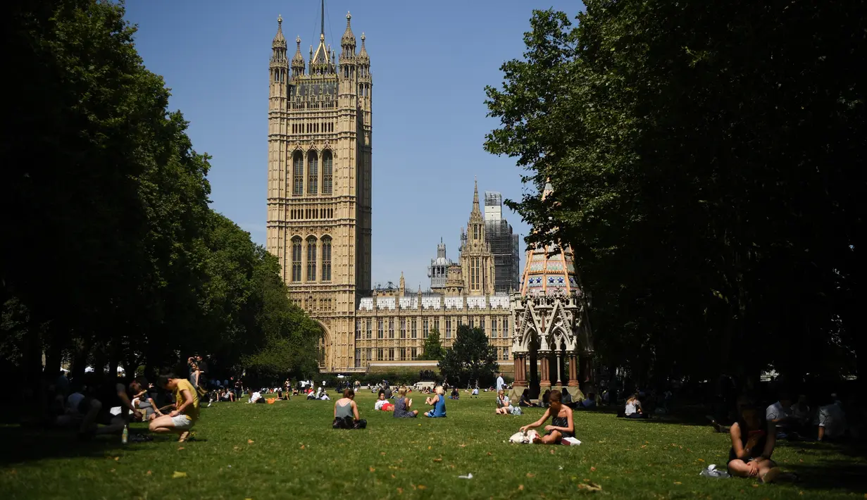 Orang-orang bersantai di bawah sinar matahari di Victoria Tower Gardens dekat Gedung Parlemen di London (23/7/2019). Suhu melonjak di atas 30C (86F) di Inggris pada 23 Juli dengan para peramal cuaca memperkirakan suhu setinggi 37C (96.8F) sebelum akhir pekan. (AFP Photo/Ben Stansall)