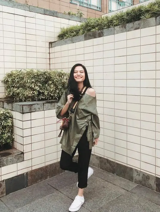 Tampil feminin dengan memadukan one shoulder top hijau army dan celana hitam (Instagram/hanggini).