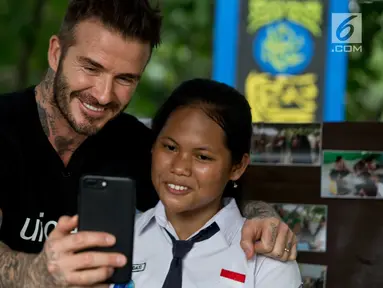 Mantan pesepakbola David Beckham berswafoto dengan siswi SMPN 17 Semarang, Sripun dalam kunjungannya sebagai Duta Kehormatan UNICEF ke Jawa Tengah, Rabu (28/3). Bersama Unicef, Beckham tengah melakukan kampanye anti-perundungan. (Liputan6.com/Pool/UNICEF)