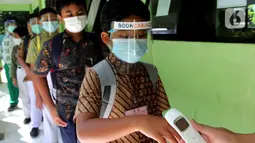 Murid di tes suhu tubuh sebelum mengikuti kegiatan Kompetisi Sains Nasional (KSN) seleksi Tingkat SD/ MI se-Kota Depok mata pelajaran IPA di SDN Kemirimuka 3, Depok, jawa Barat, Senin (22/3/2021). Pelaksanaan KSN diikuti perwakilan murid  dari 11 kecamatan di wilayah Depok. (merdeka.com/Arie Basuki)