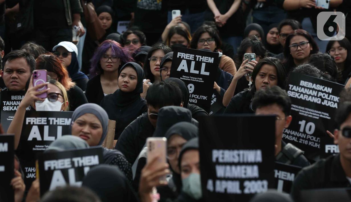 Aksi ini dikenal dengan penggunaan pakaian dan payung berwarna hitam sebagai simbol keteguhan hati dalam mencari keadilan serta duka yang tak kunjung padam karena belum tuntasnya kasus pelanggaran HAM berat di Indonesia. Tampak dalam foto, aktivis Jaringan Solidaritas Korban untuk Keadilan memegang pamflet saat mengikuti peringatan 19 tahun Aksi Kamisan di Jalan Medan Merdeka Utara atau di seberang Istana Merdeka, Jakarta, 15 Januari 2026. (Liputan6.com/Helmi Fithriansyah)