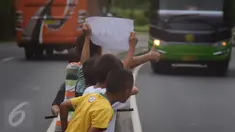 Sejumlah anak menggunakan kertas meminta bunyi klakson telolet ke bus yang lewat di jalan raya A Yani Surakarta, Solo, Kamis (22/12). Fenomena ini mendunia setelah beberapa artis dan tokoh terkenal dunia berkomentar di media sosial. (Liputan6.com/Gholib)