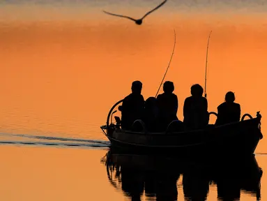 Nelayan lokal mengayuh perahu saat matahari terbenam di danau Lusiai dekat kota kecil Ignalina, sekitar 120 km (74,5 mil) utara ibukota Vilnius, Lithuania (3/6/2019). (AP Photo/Mindaugas Kulbis)
