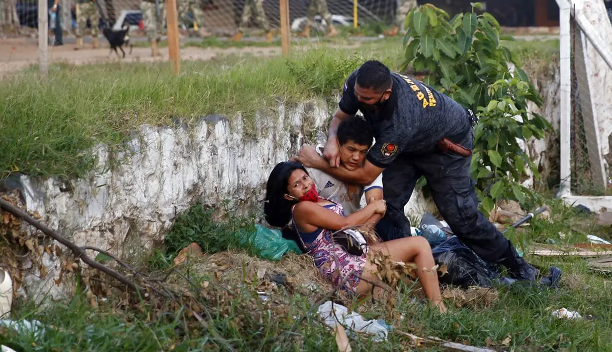 Kerabat narapidana bentrok dengan polisi di luar penjara Tacumbu  setelah kerusuhan, Asuncion, Paraguay, Selasa (16/2/2021). Sebanyak 100 narapidana di penjara terbesar di Paraguay ini merebut kekuasaan di sayap dan menyandera 18 penjaga. (AP Photo/Jorge Saenz)
