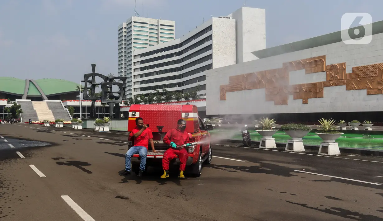 Petugas pemadam kebakaran menyemprotkan cairan disinfektan di Kompleks Parlemen, Senayan, Jakarta, Minggu (9/8/2020). Penyemprotan cairan disinfektan tersebut dilakukan dalam rangka pencegahan penyebaran virus Corona (COVID-19) di lingkungan DPR/MPR. (Liputan6.com/Johan Tallo)