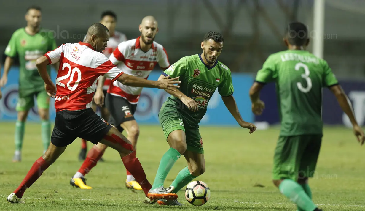 Striker Madura United, Thiago Furtuoso, berusaha merebut bola dari pemain PS TNI, Redouane Zerzouri, pada laga Liga 1 Indonesia di Stadion Pakansari, Bogor, Senin (18/9/2017). Madura United menang 3-2 atas PS TNI. (Bola.com/M Iqbal Ichsan)