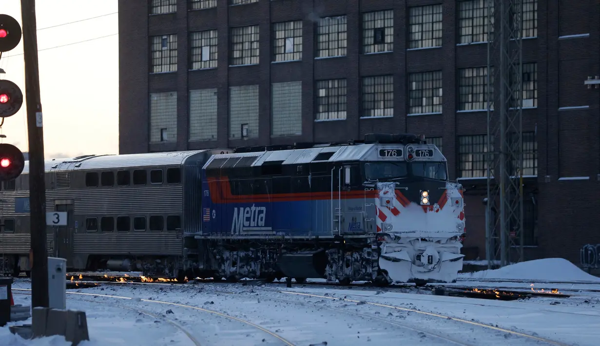 Sebuah kereta komuter melaju menuju pusat kota Chicago ketika api menyala di sepanjang rel di dekat stasiun Metra Western Avenue, 29 Januari 2019. Metra memakai sistem pemanas berbahan bakar gas untuk menghangatkan lintasan yang dingin. (AP/Kiichiro Sato)