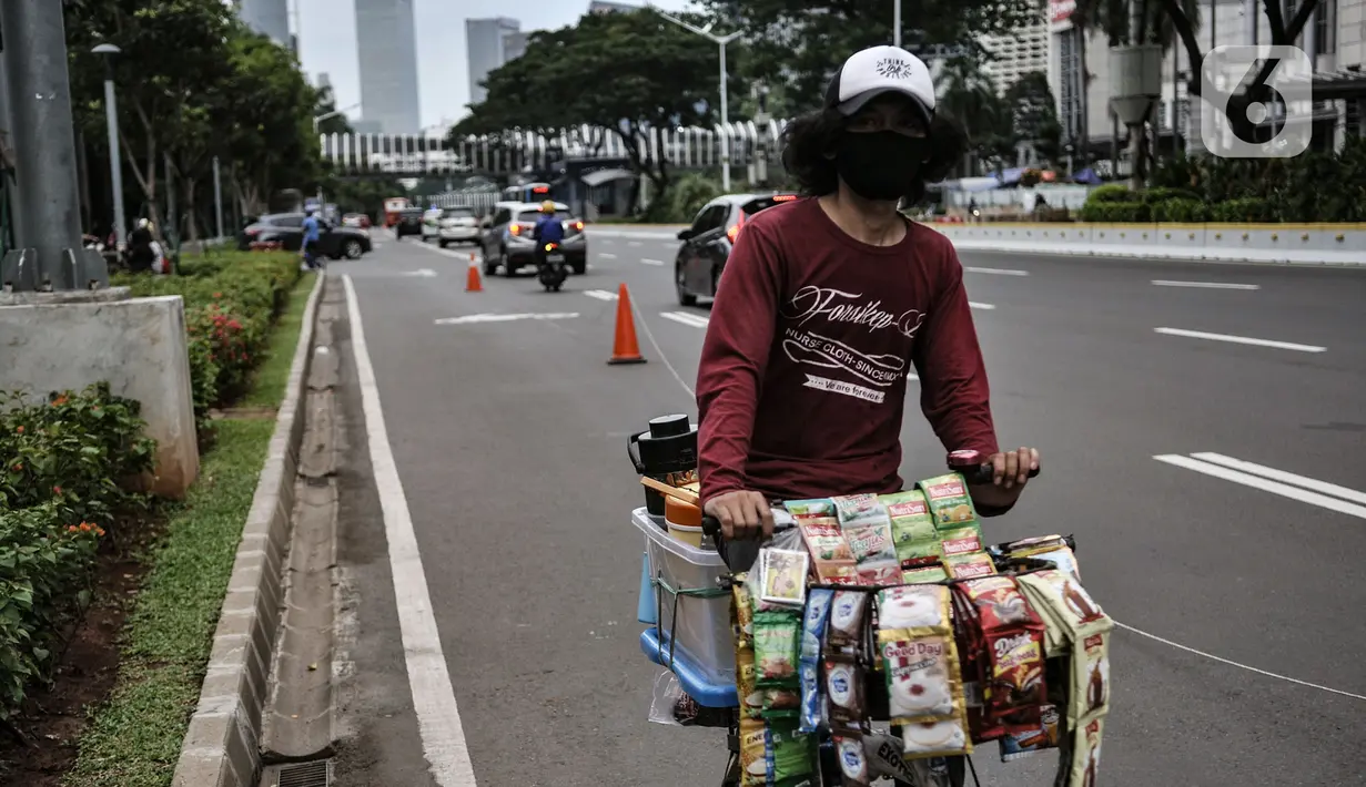 Pedagang kopi keliling saat melintas di Jalan Jenderal Soedirman, Jakarta, Minggu (11/10/2020). Gugus Tugas Percepatan Penanganan Covid-19 mencatat adanya pelambatan kenaikan kasus positif atau aktif di Ibu Kota selama sebulan pemberlakukan PSBB yang diperketat. (merdeka.com/Iqbal S. Nugroho)