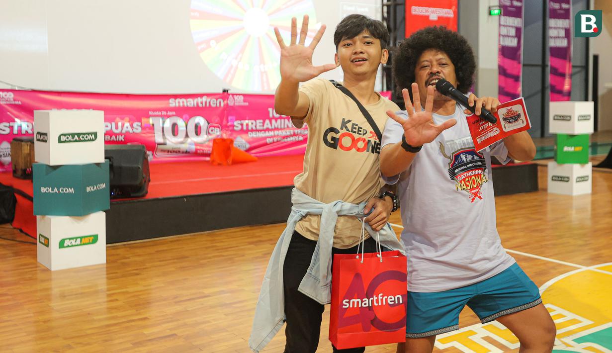 Salah seorang peserta Roaring Night pertandingan Liga Inggris 2023/2024 antara Arsenal kontra Crystal Palace yang beruntung mendapatkan merchandise dari sponsor berfoto bersama MC Eddi Brokoli di Bucketlist Indonesia, Bogor, Sabtu (20/1/2024). (Bola.com/Bagaskara Lazuardi)