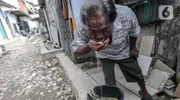 Seorang warga meminum air di kawasan Muara Angke, Jakarta, Sabtu (26/2/2022). Sejak tahun 1980-an, warga Muara Angke, Jakarta Utara, mengalami kesulitan mendapatkan air bersih. (Liputan6.com/Faizal Fanani)