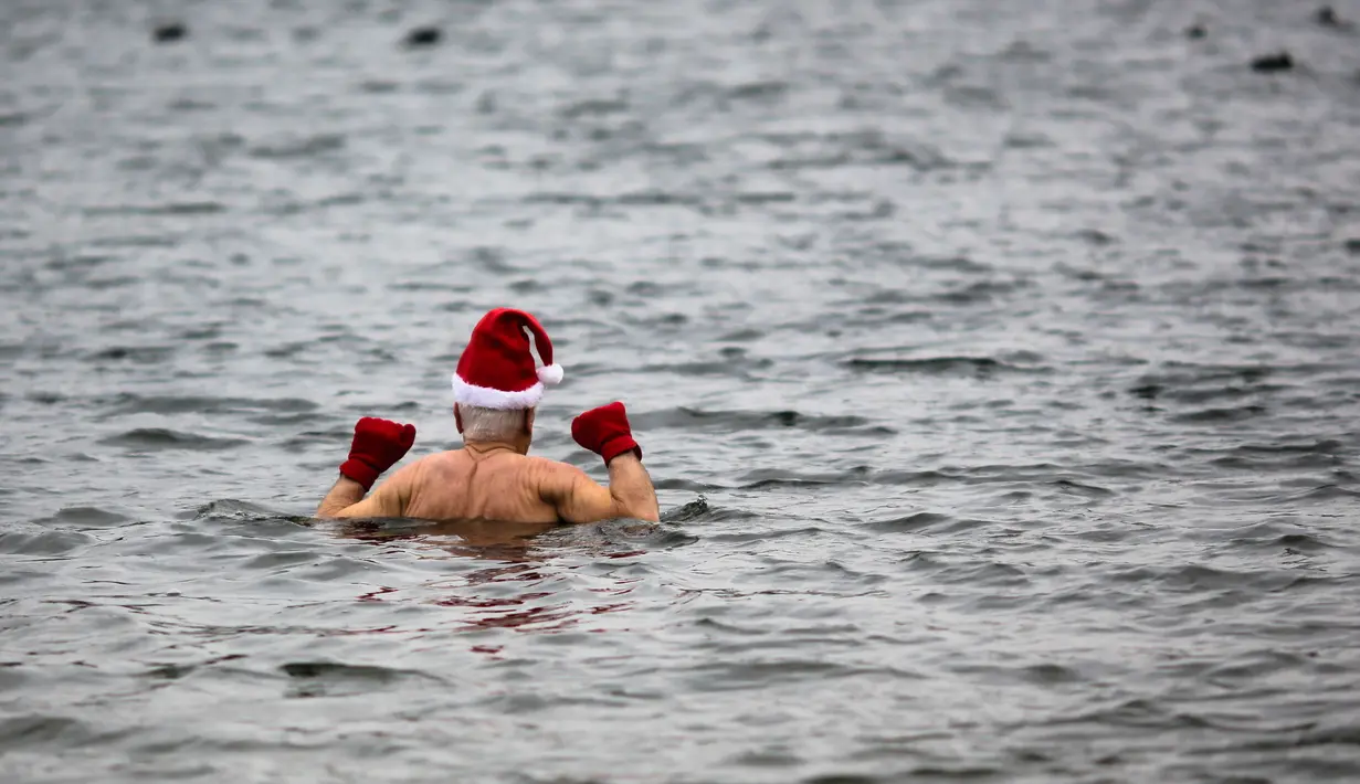 Anggota klub renang "Berliner Seehunde" (Berlin Seals) turun ke danau Orankesee sebagai bagian dari tradisi berenang pada Natal di Berlin, Jerman, Senin (25/12). Kegiatan ini salah satu tradisi di Berlin menyambut Natal setiap tahun. (AP/Markus Schreiber)