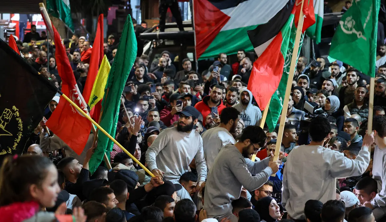 Para tahanan bersorak di antara para pendukungnya setelah dibebaskan dari penjara Israel di Ramallah, Tepi Barat yang diduduki, pada tanggal 26 November 2023. (Jaafar ASHTIYEH/AFP)