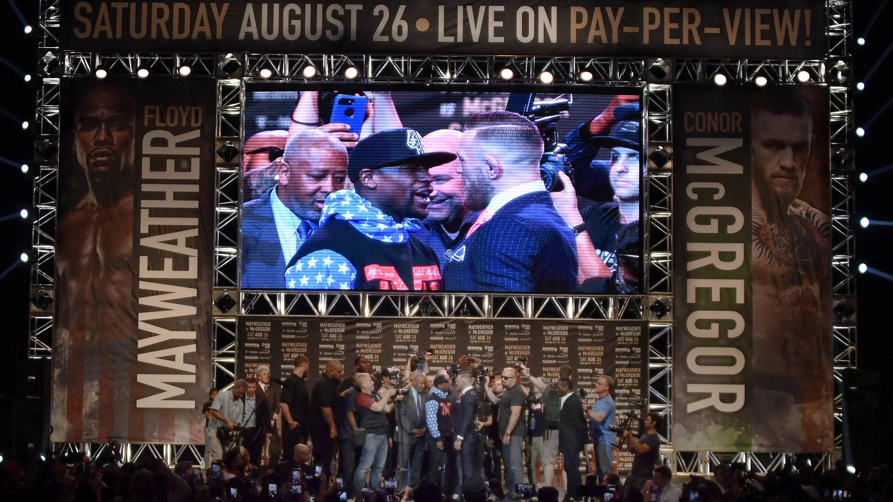 Layar besar Staples Center menunjukkan adu mulut Floyd Mayweather Jr dan Conor McGregor pada konferensi pers pertama jelang duel. (AFP/Gene Blevins)