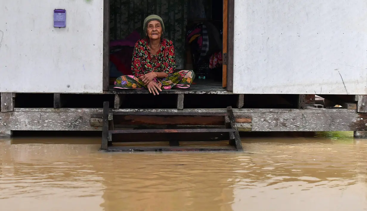 Seorang warga melihat banjir dari rumahnya di distrik Ran-ngea di provinsi Narathiwat, Thailand selatan (26/2/2022).  Hujan yang disebabkan oleh angin timur laut di atas Teluk Thailand terus berlanjut selama tiga hari berturut-turut di provinsi perbatasan selatan ini. (AFP/Madaree Tohlala)
