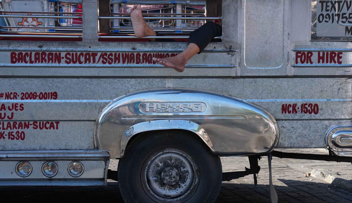 Kebijakan ini berlaku terbatas bagi kendaraan produksi 2015 ke bawah, seperti jeepney (angkutan umum tradisional Filipina), pembangkit listrik, generator, serta sektor maritim, dan pelayaran. Tampak dalam foto, seorang pengemudi jeepney beristirahat sejenak sambil menunggu giliran di terminal kota Pasay, Filipina, pada Senin, 23 Maret 2026. (AP Photo/Aaron Favila)