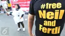 Seorang pria mengenakan kaos yang menghimbau untuk melepaskan Neil dan Ferdi terkait kasus JIS saat menggelar flashmob di Jalan Jenderal Sudirman, Jakarta, Minggu (5/3). (Liputan6.com/Helmi Afandi)