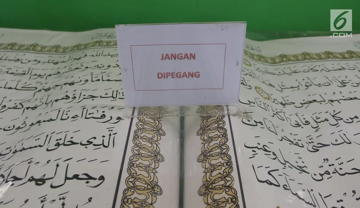 Sebuah tulisan "Jangan Dipegang" diletakkan di atas Alquran raksasa yang dipajang di perpustakaan Jakarta Islamic Centre, Jakarta Utara, Jumat (18/5). Alquran yang ditulis tangan tersebut dibuat pada tahun 2002 di Wonosobo. (Liputan6.com/Arya Manggala)