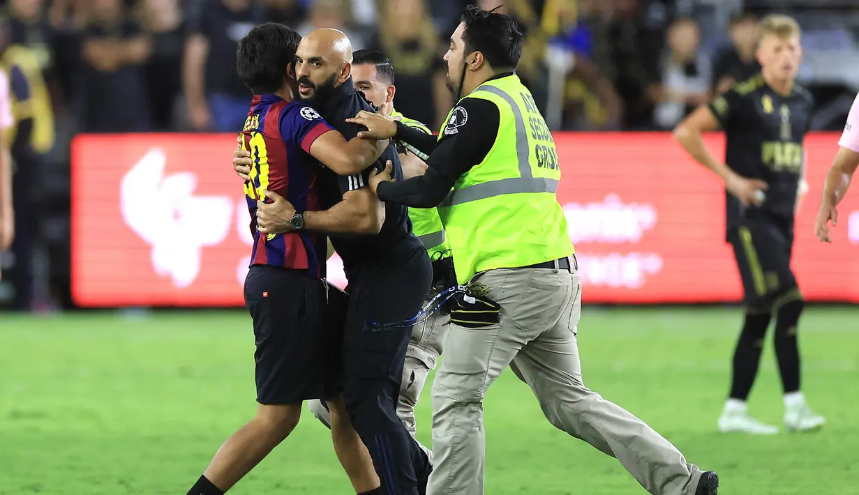 <p>Fans itu berlari ke arah Lionel Messi dan mencoba memeluk LM10. Keinginannya itu batal terwujud setelah Yassine Chueko berlari dan menangkapnya. (Sean M. Haffey/Getty Images/AFP)</p>