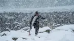 Seorang surfer atau peselancar berjalan keluar dari air di bawah hujan salju di Unstad, Norwegia Utara (11/3). Pria ini berselancar di wiliyah Lingkaran Arktik dengan suhu minus 13 derajat Celsius. (AFP Photo/Olivier Morin)