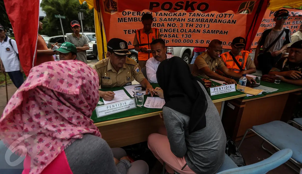 Pengunjung car free day (CFD) mengisi surat pernyataan di sebuah posko Operasi Tangkap Tangan (OTT) kawasan Bundaran HI, Jakarta, Minggu (29/1). Pengunjung tersebut kedapatan membuang sampah sembarang di arena CFD. Liputan6.com/Faizal Fanani)