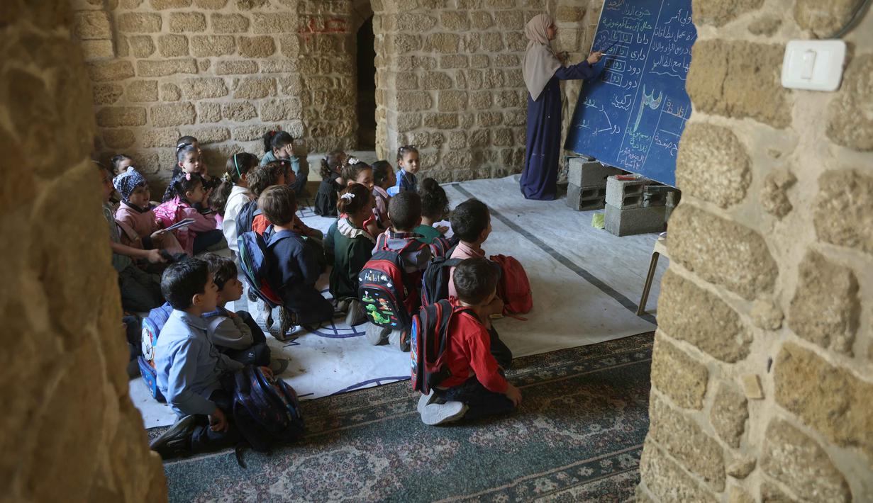 Anak-anak Palestina menghadiri kelas di sekolah bersejarah "Al-Kamaliya al-Othmanya" di Kota Tua Gaza yang menjadi bagian dari inisiatif sukarelawan yang diorganisir oleh para guru pengungsi, di Kota Gaza pada 2 November 2025. Anak-anak pengungsi Palestina di Gaza akan secara bertahap kembali ke sekolah. (Omar AL-QATTAA/AFP)