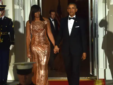 Kemesraan Presiden AS Barack Obama dan Michelle Obama saat menunggu kedatangan PM Italia Matteo Renzi dan Agnese Landini di Gedung Putih, Washington, Selasa (18/10). Malam itu, Michelle tampil cantik berbalut gaun rancangan Versace. (Nicholas Kamm/AFP)