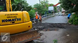 Petugas melakukan perbaikan Jembatan Inspeksi Kali Grogol yang ambles di Komplek Hankam, Slipi, Jakarta, Senin (21/3). Amblesnya jembatan juga akibat pondasi jembatan bergeser dan permukaan jalan amblas. (Liputan6.com/Faisal R Syam)