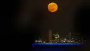 Orang-orang menyaksikan bulan penuh yang disebut sebagai Buck Moon  terbit di atas cakrawala Kota Kuwait pada Senin, 3 Juli 2023. (YASSER AL-ZAYYAT / AFP)