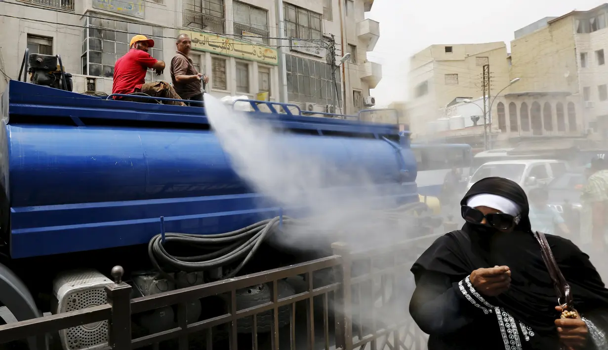 Personel dinas Kota Amman menyemprot warga dengan sprinkler air untuk mengurangi efek dari gelombang panas di Yordania, Senin(3/8/2015). (REUTERS/Muhammad Hamed)