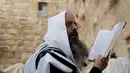 Seorang pria dari Kohanim atau kasta imam Yahudi berdoa menjelang Paskah di depan Tembok Barat, Yerusalem (13/4). Kohanim diyakini keturunan imam yang melayani Tuhan di kuil Yahudi sebelum dihancurkan. (AP Photo / Ariel Schalit) 