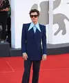 Harry Styles memakai setelan biru bercelana flared kemeja sutra biru muda berkerah runcing. Serta sepatu bot kuli putih dari Gucci HA HA HA plus kacamata cokelat bingkai persegi untuk melengkapi ansambelnya di premiere 'Don't Worry Darling' (Foto: Gucci)