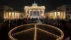 Para aktivis meletakkan lilin yang membentuk tanda perdamaian di depan Gerbang Brandenburg, menjelang peringatan satu tahun invasi Rusia ke Ukraina, di Berlin, Jerman, Kamis (23/2). Setahun sudah invasi Rusia ke Ukraina berlangsung. Namun, hingga kini belum ada tanda-tanda Rusia ingin mengakhiri agresi dan berdamai. (Paul Zinken/dpa via AP)