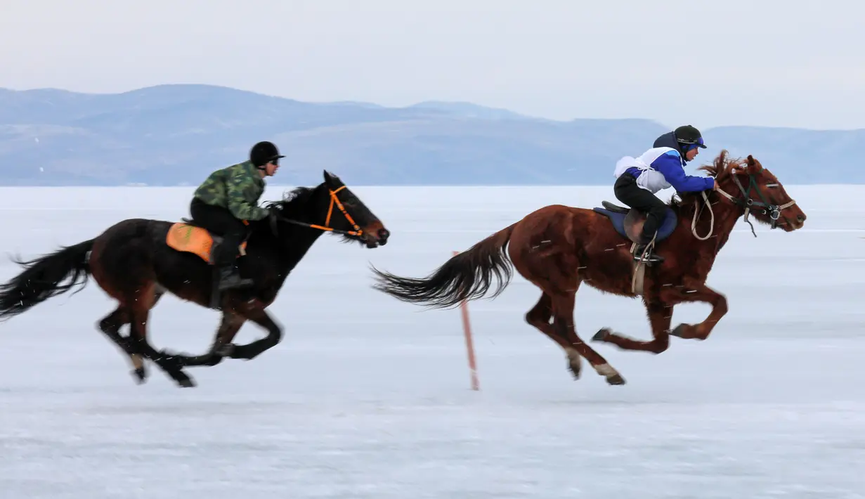 Dua peserta memacu kudanya selama bersaing dalam balapan kuda Ice Derby di Sungai Yenisei yang membeku, Krasnoyarsk, Rusia (16/3). (Reuters/Ilya Naymushin)