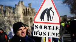Seorang pria memegang tanda bertuliskan "keluar dari pabrik" selama demonstrasi pada hari kelima demonstrasi nasional yang diselenggarakan sejak awal tahun, menentang perombakan pensiun yang sangat tidak populer, di Avignon, Prancis Selatan, Kamis (16/2/2023). (CHRISTOPHE SIMON/AFP)