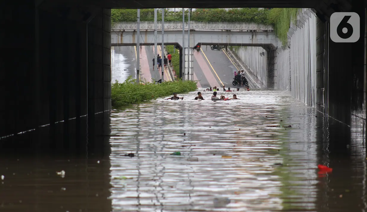 Warga bermain di terowongan Jalan Angkasa, Jakarta, Selasa (25/2/2020). Hujan yang mengguyur Jakarta sejak Senin (24/2) malam membuat sejumlah kali meluap dan menyebabkan banjir di terowongan tersebut. (Liputan6.com/Helmi Fithriansyah)