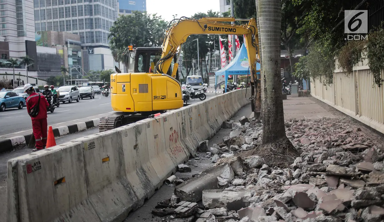 Pekerja dibantu alat berat merevitalisasi trotoar di kawasan Bundaran HI, Jakarta Pusat, Senin (15/7/2019). Penantaan ini dilakukan untuk mempercantik trotoar dan memberikan rasa nyaman bagi pejalan kaki. (Liputan6.com/Faizal Fanani)