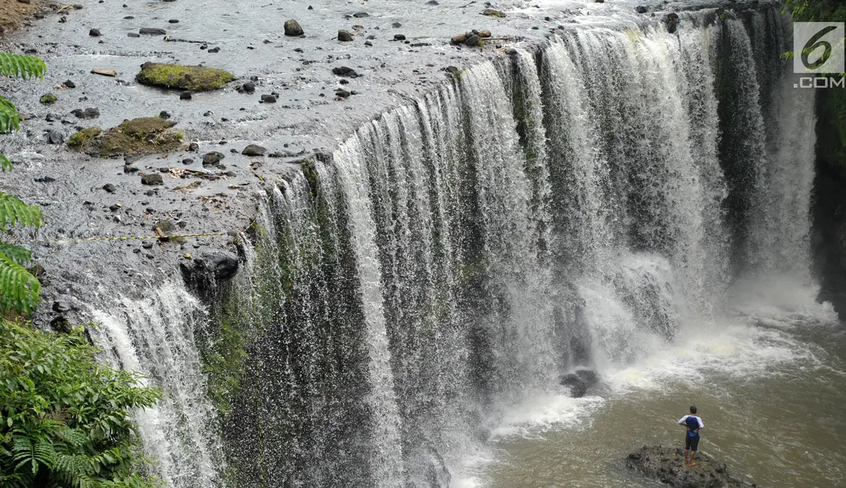 Wisatawan menikmati air terjun Temam di Kota Lubuklinggau, Sumatera Selatan, Rabu (10/1). Air terjun ini memiliki ketinggian 12 meter dengan lebar 25 meter dan menghasilkan guyuran air yang menyerupai tirai raksasa. (Liputan6.com/Immanuel Antonius)