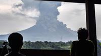 Penduduk desa melihat asap abu vulkanik Gunung Sinabung dari kota Karo (6/4). Gunung Sinabung di Kabupaten Karo, Sumatera Utara, kembali meletus, pada Jumat (6/4/2018) pukul 16.07 WIB. (AFP Photo/Anto Sembiring)