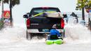 Sebuah truk menarik seorang pria di atas kayak di jalan dataran rendah setelah banjir karena Badai Ian, Key West, Florida, Amerika Serikat, 28 September 2022. (AP Photo/Mary Martin)