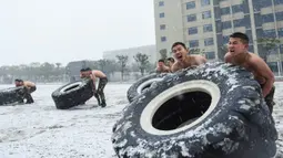 Polisi militer China mengangkat ban saat sesi pelatihan di tengah hujan salju di Hefei, Provinsi Anhui, China (15/1/2020). Latihan fisik yang dilakukan anggota polisi militer China meliput angkat ban traktor sampai dengan teknik menyerang dengan menggunakan senapan berpisau. (AFP Photo/Str/China Out