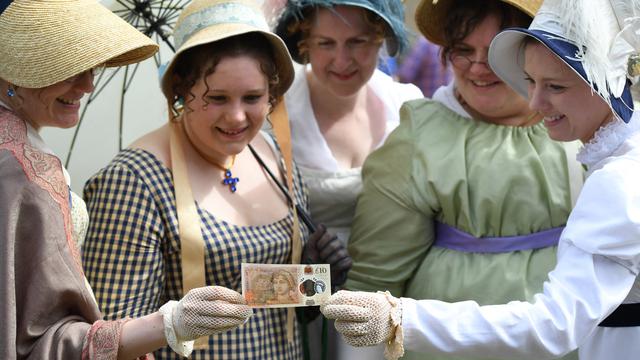 Orang-orang dengan kostum zaman dahulu berpose di atas uang kertas sepuluh pound baru Bank of England, yang menampilkan penulis Jane Austen, saat peluncurannya di Katedral Winchester di Winchester, Inggris selatan, pada 18 Juli 2017.