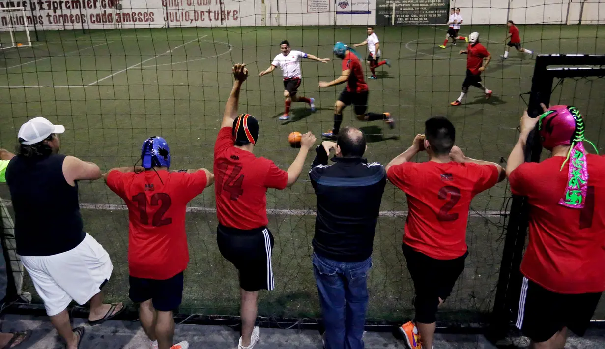 Sejumlah Pegulat berdiri melihat rekan satu tim mereka bermain futsal di Monterrey, Meksiko (29/2). Sejumlah pegulat profesional Meksiko mencoba hal baru bermain futsal untuk menjalin persahabatan di antara pegulat. (REUTERS/Daniel Becerril)