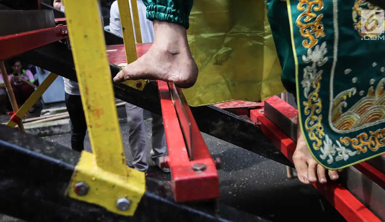 Tatung pria berjalan menaiki tangga dari susunan tombak saat beratraksi dalam Festival Cap Go Meh 2570 di Seasons City, Jakarta,  Minggu (24/3). Acara ini diikuti oleh sekitar 100 tatung pria dan wanita. (Liputan6.com/Fery Pradolo)