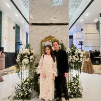 Gaya manis pasangan Dul Jaelani dan Tissa Biani saat kondangan. Tissa Biani tampil cantik dengan dress lace berwarna putih, sedangkan Dul tampil serba hitam dengan kemeja lengan panjang berwarna hitam dan celana panjangnya. [Foto: Instagram/tissabiani]