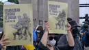 Para mahasiswa menunjukkan plakat bertuliskan “Kembalikan Tentara ke Barak” dalam sebuah protes menentang Revisi Undang-Undang Tentara Nasional Indonesia (RUU TNI) di depan gedung DPR di Jakarta pada tanggal 20 Maret 2025. (BAY ISMOYO/AFP)